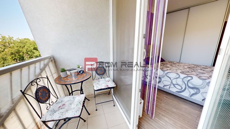 A balcony with metal furniture and a view, connected to a room in a 2-room apartment.