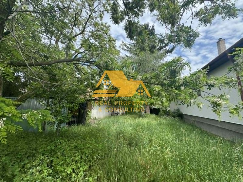 A residential plot in Andovce with lush greenery and a house in the background.