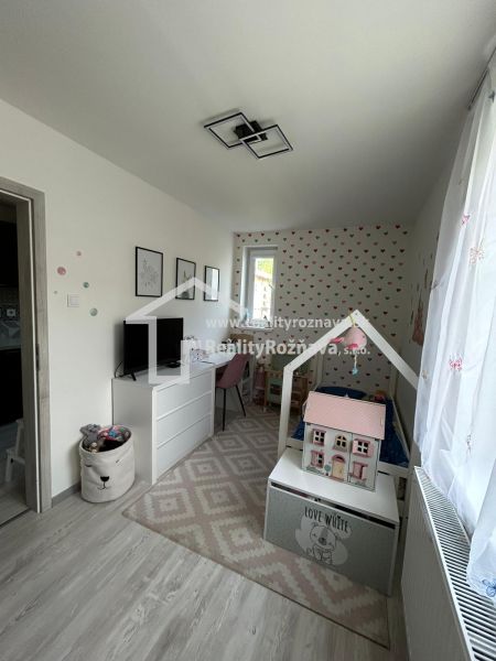 Children's room in a three-room apartment with wood-patterned flooring and decorative wallpaper.