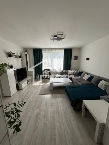 Living room with a corner sofa, TV, and floor with wood decor in a 3-room apartment.