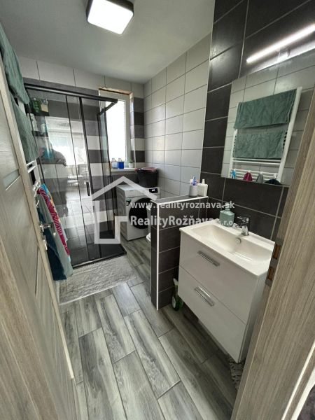 A bathroom in a 3-room apartment with a wooden decor floor and a shower corner.