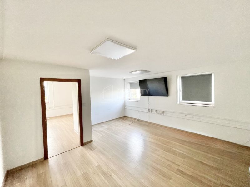The interior of offices with wood-patterned flooring and a television on the wall.