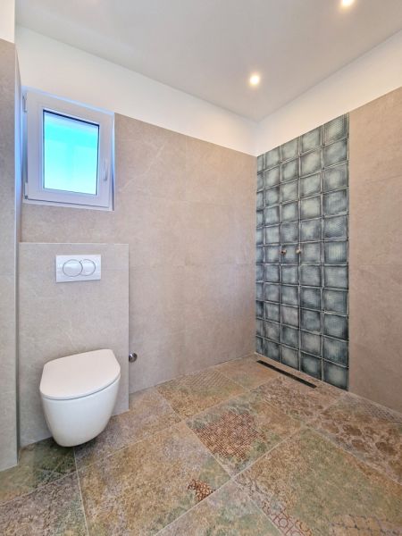 Bathroom in a 3-room apartment with wall tiles and floor with decor.