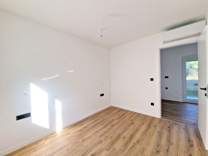 A room in a 3-room apartment with a wooden decor floor, light walls, doors open.