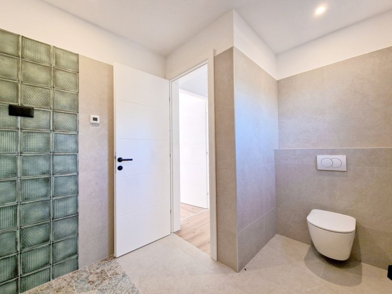 A bathroom in a 3-room apartment with ceramic tiles and a wooden decor floor.