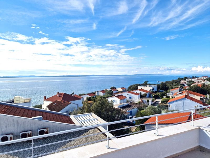 A view from a 3-room apartment in Petrcane of the sea and rooftops of houses.