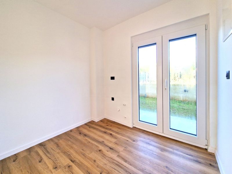 A room in a 3-room apartment with white walls and a wooden decor floor.