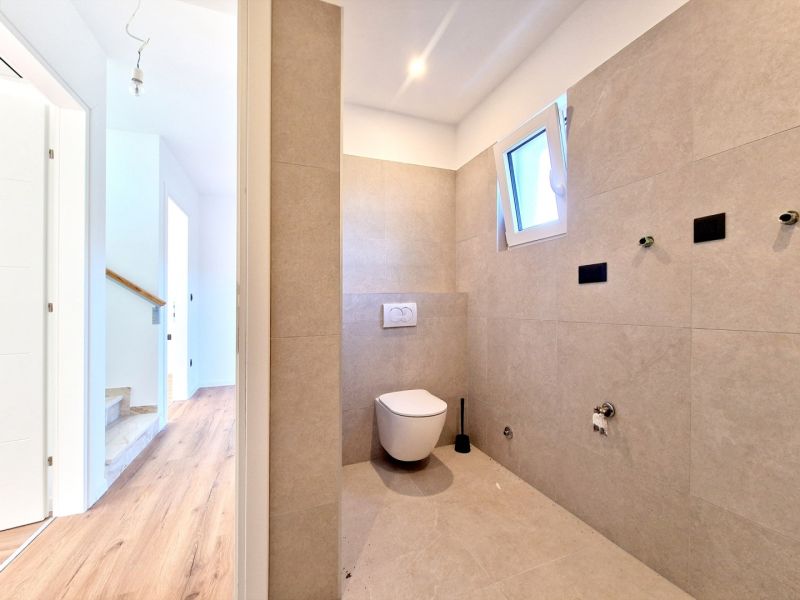 A toilet in a 3-room apartment with a minimalist design and a wooden decor floor.