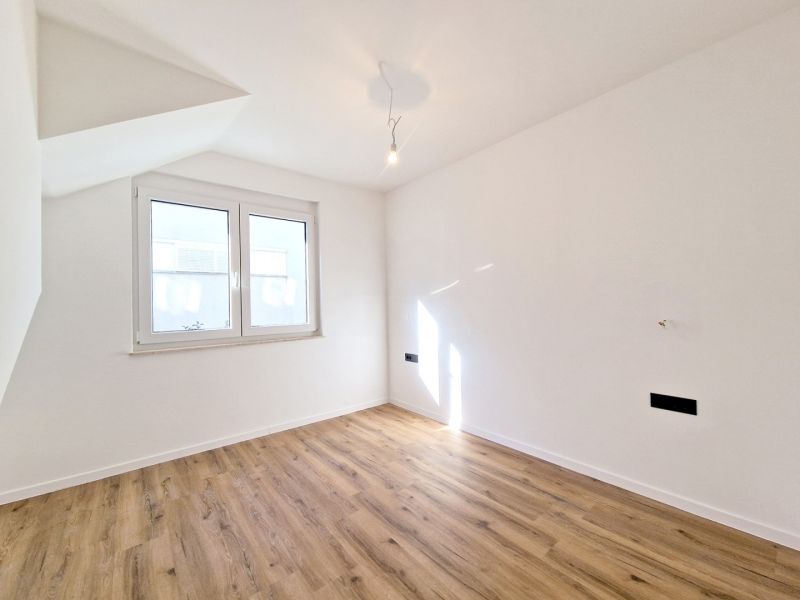 A room with white walls and a floor with a wooden decor in a 3-room apartment.