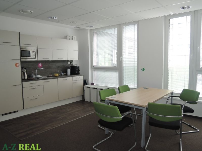Offices with a kitchenette, wooden decor flooring, and green chairs.