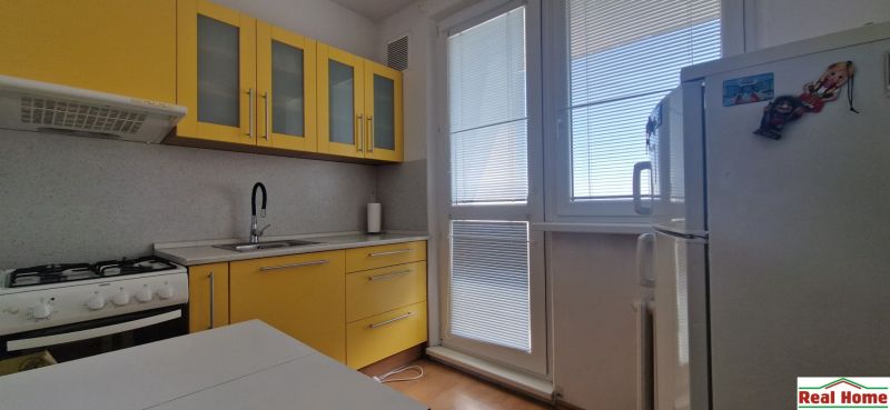 A kitchen with yellow cabinets in a 2-room apartment, floor with wood decor.