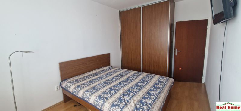 Bedroom in a 2-room apartment with a bed, wardrobe, and wooden decor flooring.