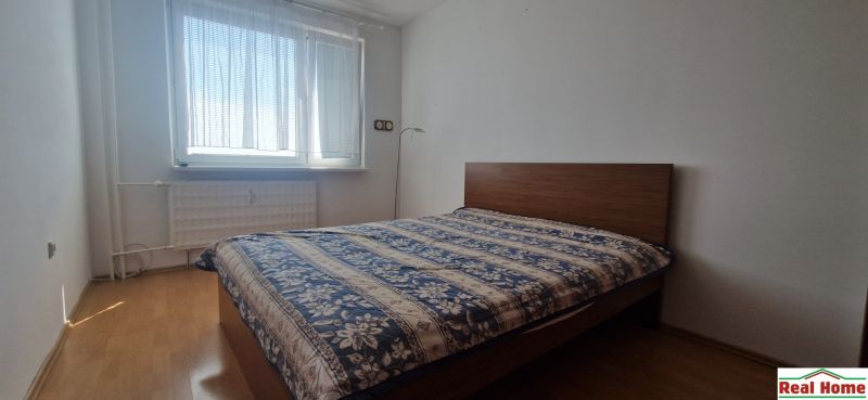 Bedroom with a bed and wooden decor flooring in a 2-room apartment.