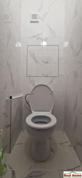 A toilet with ceramic tiles in a 2-room apartment.