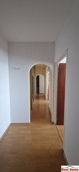 A hallway with an arched passage and a wooden decor floor in a 2-room apartment.