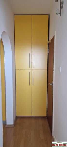 A hallway with a yellow built-in wardrobe and a floor with a wooden decor in a 2-room apartment.