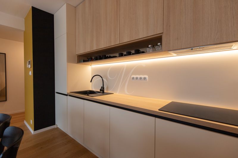 Kitchen unit with storage space, black sink, and cooktop in a 2-room apartment.
