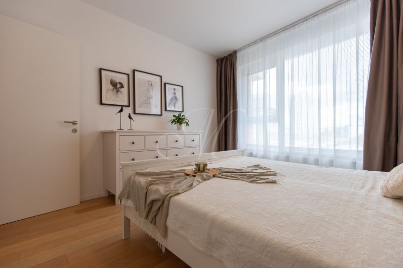 Bedroom with white furniture in a two-room apartment, floor with wood decor.