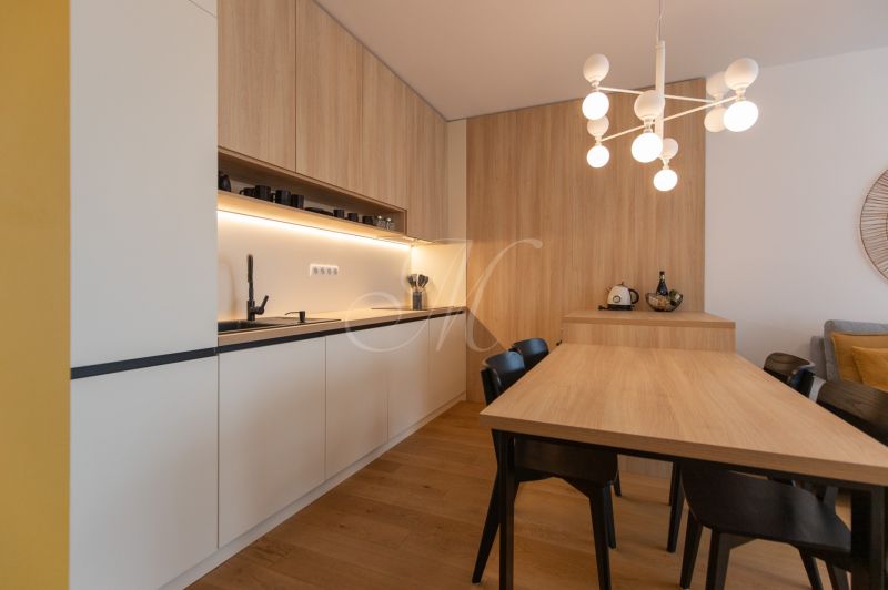 A kitchen in a 2-room apartment with a wooden decor floor and a dining table.