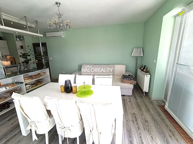 Bright living space with a dining table and wood-patterned flooring in a three-room apartment.