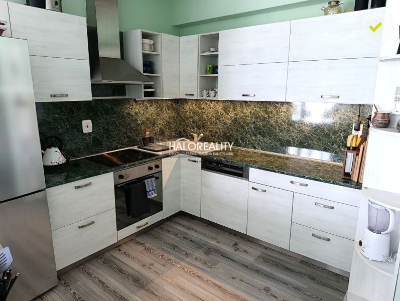 A kitchen in a 3-room apartment with a wooden decor floor and green tiles.