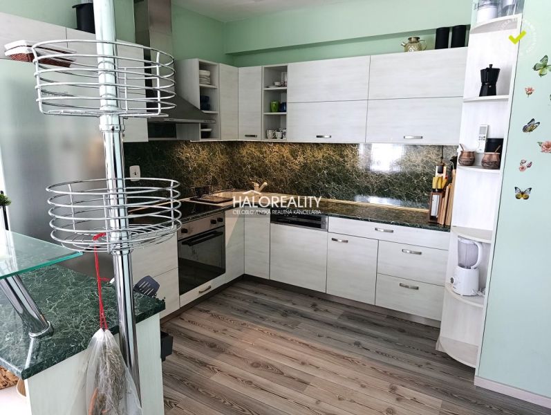 A kitchen in a 3-room apartment with a wooden decor floor and green tiles.