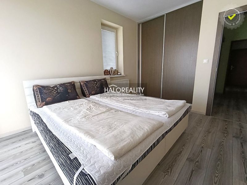 A bedroom in a three-room apartment with a wooden decor floor and a built-in wardrobe.