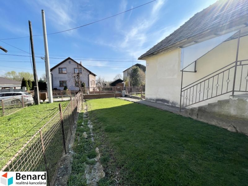 The garden of the family house on Tehelna Street in Drienov with a manicured lawn and fencing.