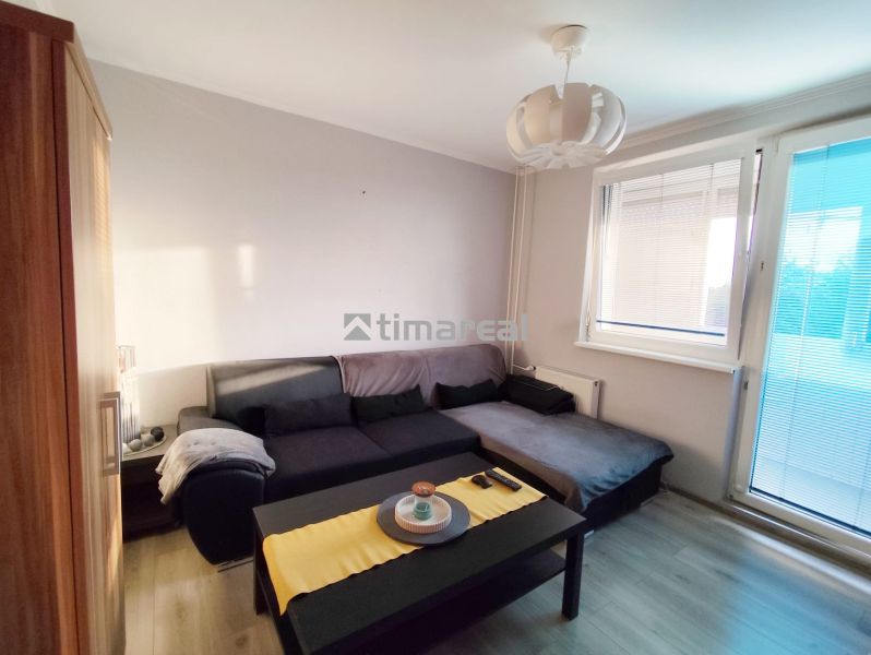 Living room with a sofa and a table in a two-room apartment, floor with wooden decor.