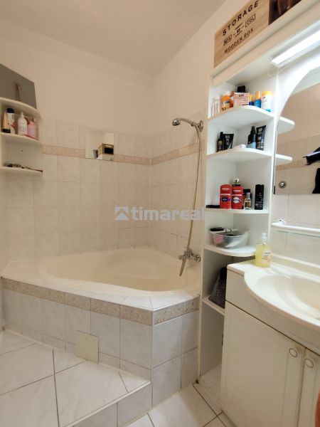Bathroom in a 2-room apartment with tiles, a bathtub, and storage space.