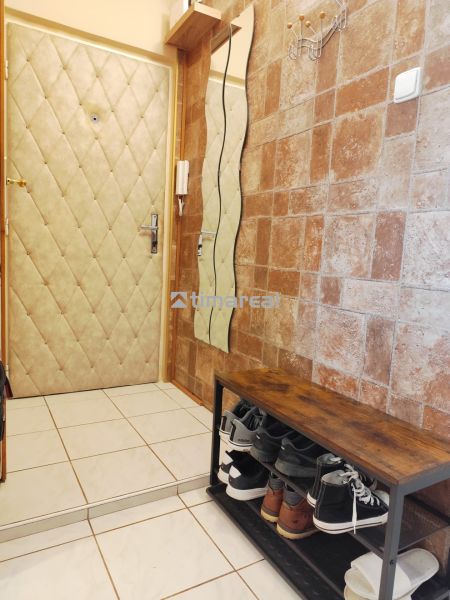 Entrance hall in a 2-room apartment with a shoe cabinet, coat rack, cladding, and tiles.