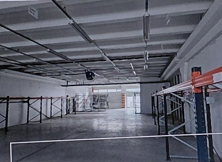 Spacious warehouses and halls with metal shelves and concrete floors.