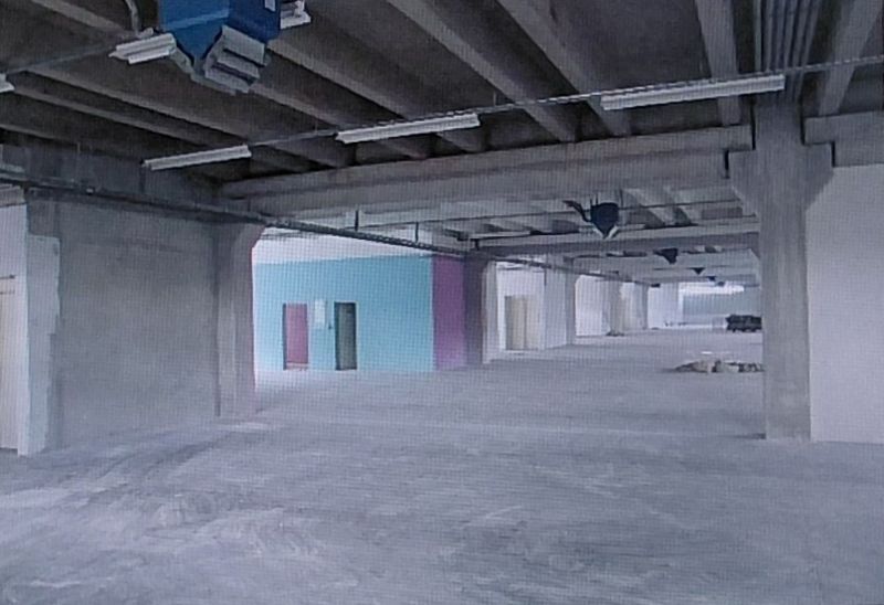 A vast empty space in warehouses and halls with concrete columns and a colorful wall.