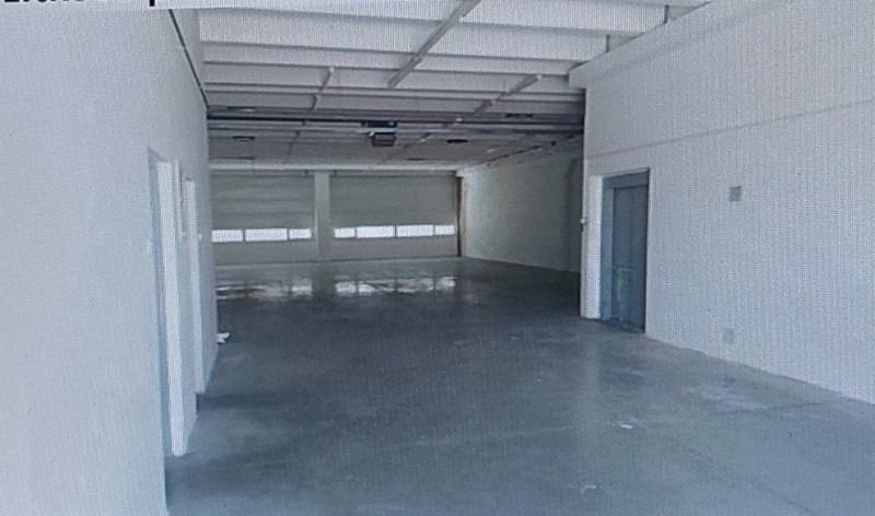 A spacious interior of a warehouse and hall with a concrete floor and white walls.