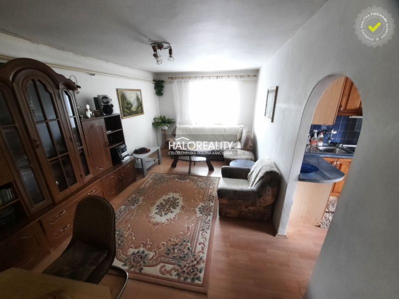 Living room with a sofa, antique cabinet, and wooden decor flooring in a family house.