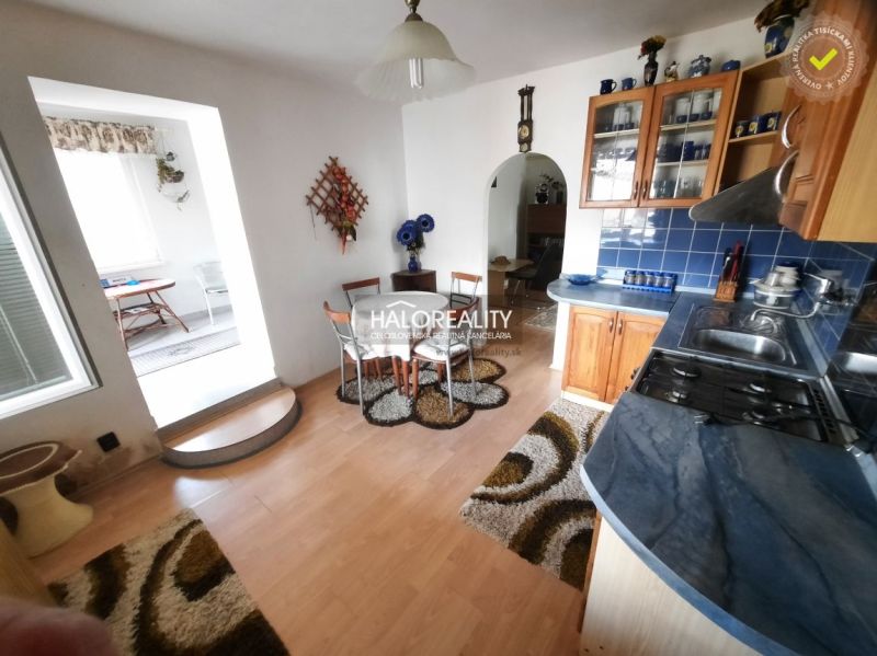 A kitchen in a family house with blue tiles and a wooden decor floor.