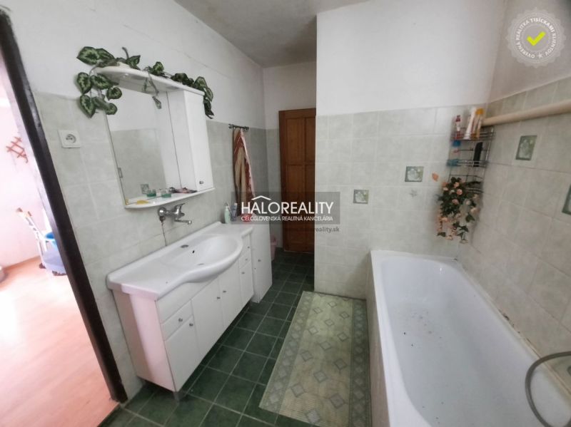 A bathroom with a bathtub and a white sink in a family house, green tiles.