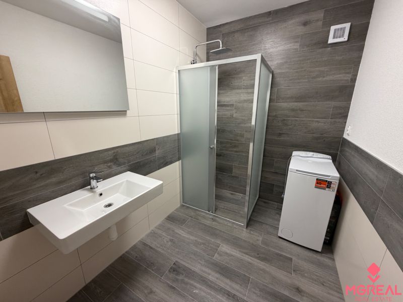 Bathroom in a 3-room apartment with a sink, shower, and washing machine.