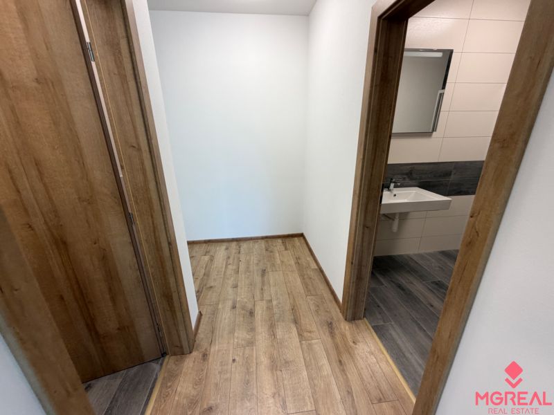 A hallway of a 3-room apartment with a wooden decor floor and a view into the bathroom.