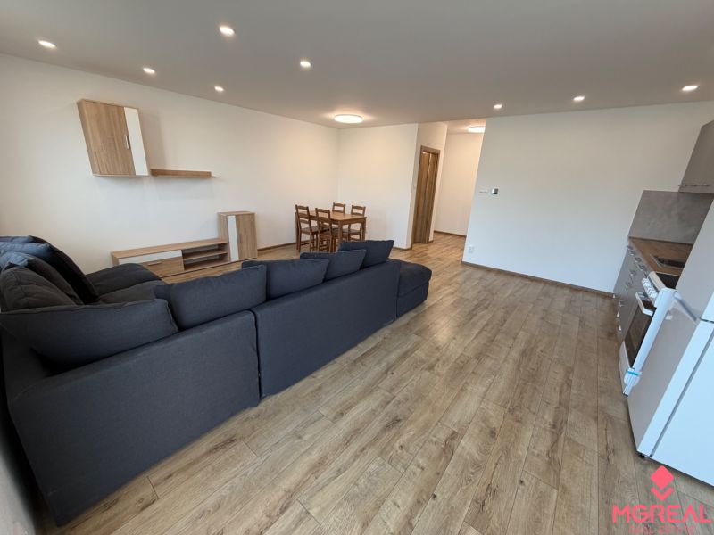 Living room of a three-room apartment with a corner sofa and a floor with a wooden decor.