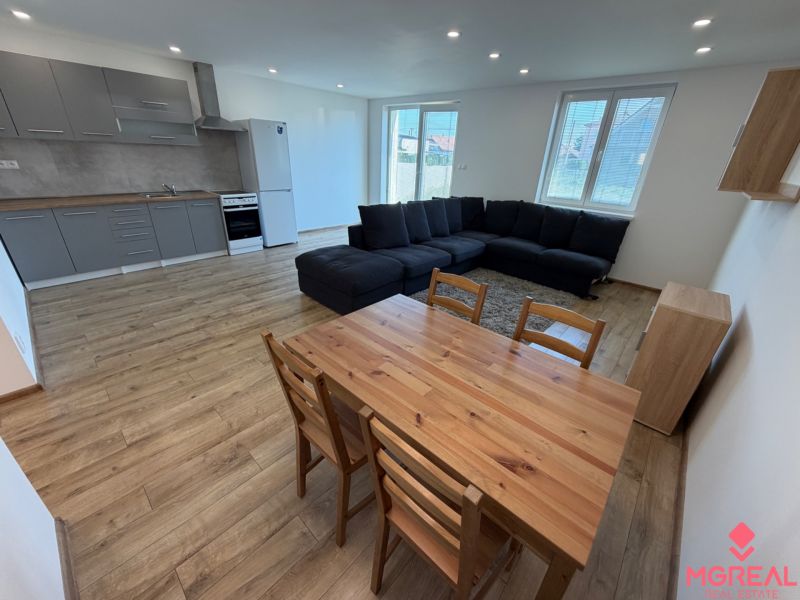 Living room with kitchen in a 3-room apartment with a wooden decor floor and a large sofa.