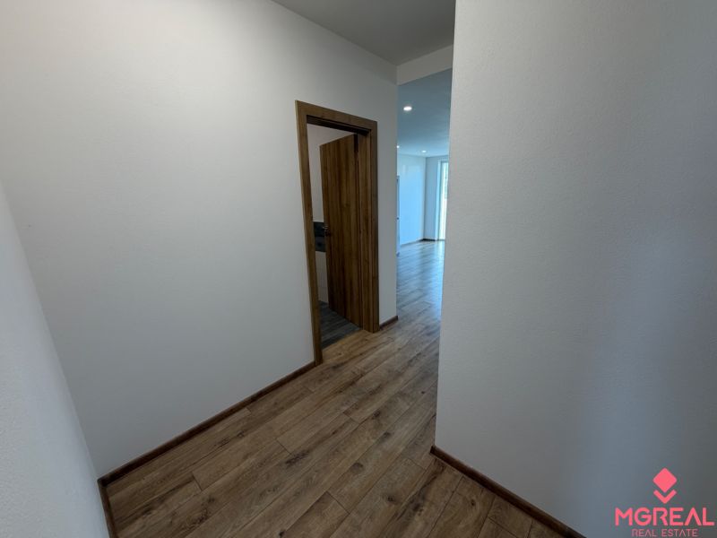 A hallway in a 3-room apartment with a wooden decor floor and white walls.