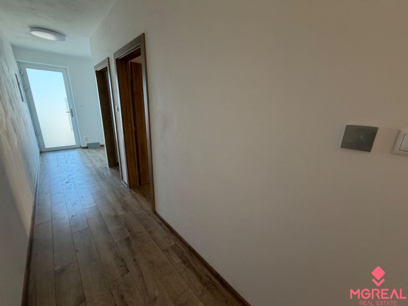 A hallway with a wooden decor floor and doors in a 3-room apartment.