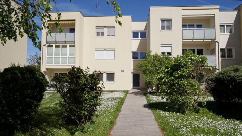 Apartment building on Spechtgasse in Mödling with a garden and a walkway in the foreground.