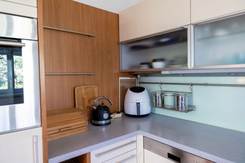 A kitchen in a 3-room apartment with a wooden decor on the wall and appliances.