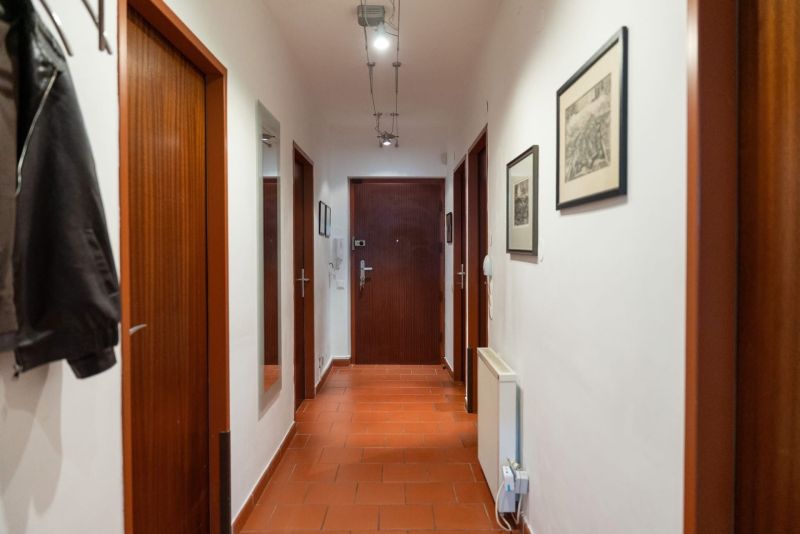 A hallway with a mirror, paintings, and a reddish-brown floor in a 3-room apartment.