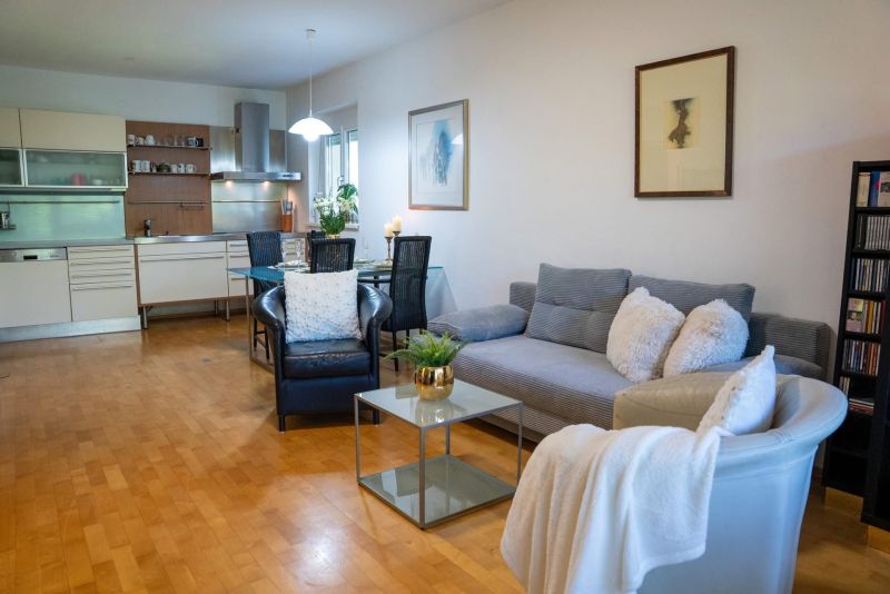 Living room with kitchen in a 3-room apartment, wooden decor flooring, comfortable couch.