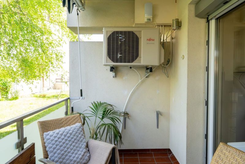 Balcony of a 3-room apartment on Spechtgasse in Mödling with air conditioning and a plant.