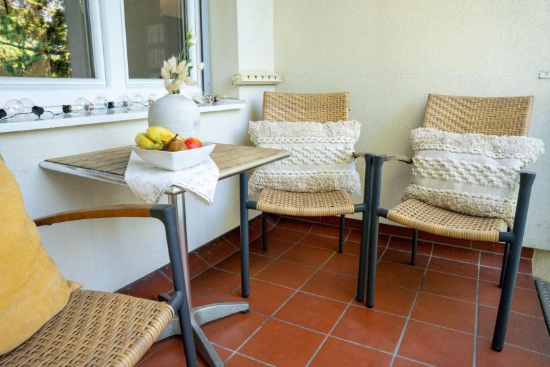 Three chairs and a table with a bowl of fruit on the terrace, 3-room apartment.