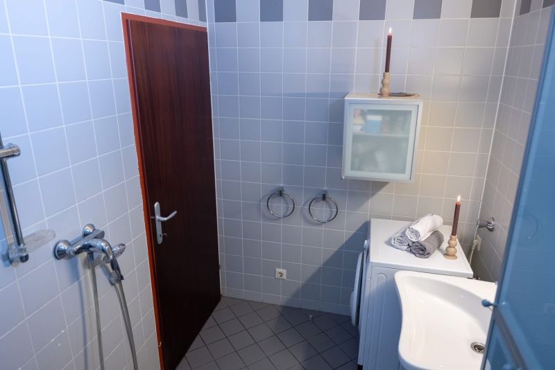 Bathroom in a 3-room apartment with tiles, a washing machine, and a cabinet.
